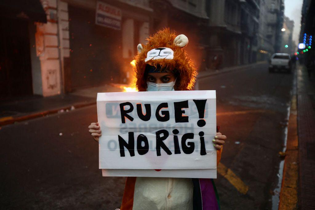 Una persona disfrazada de tigre sostiene un cartel que dice Ruge! No Rigi