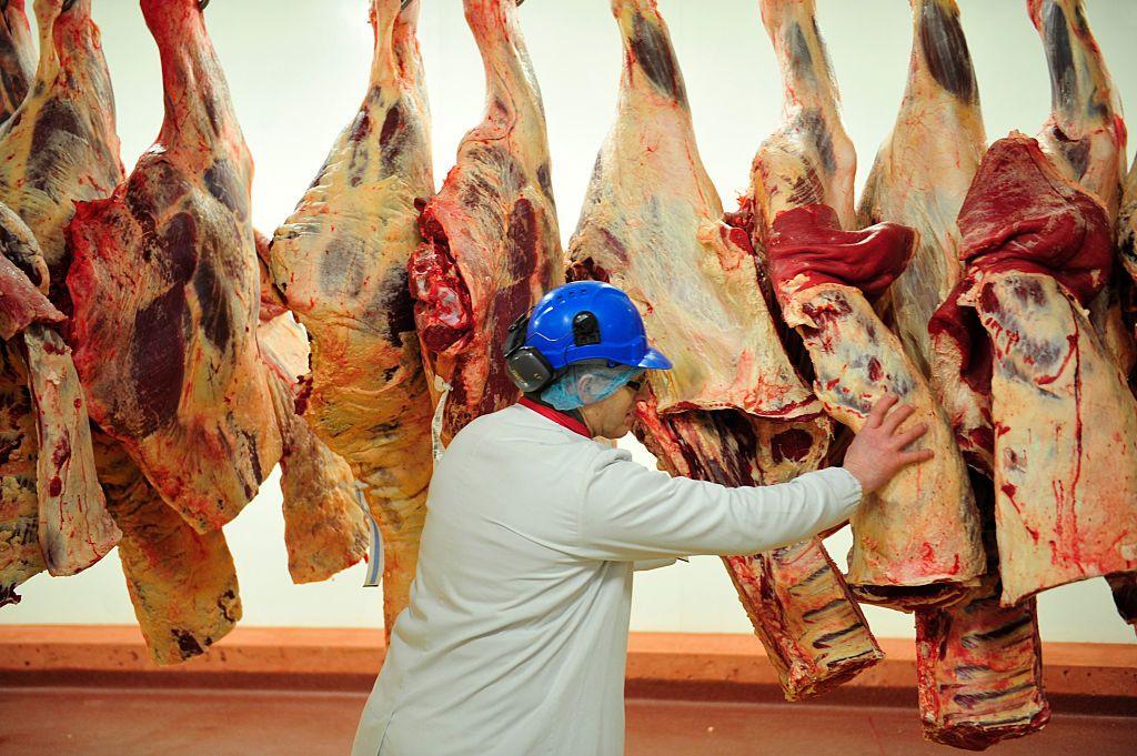 Trabalhador mexe em peças de carne penduradas