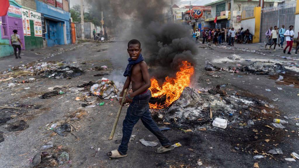 Un hombre camina frente a un neumático en llamas en Haití 