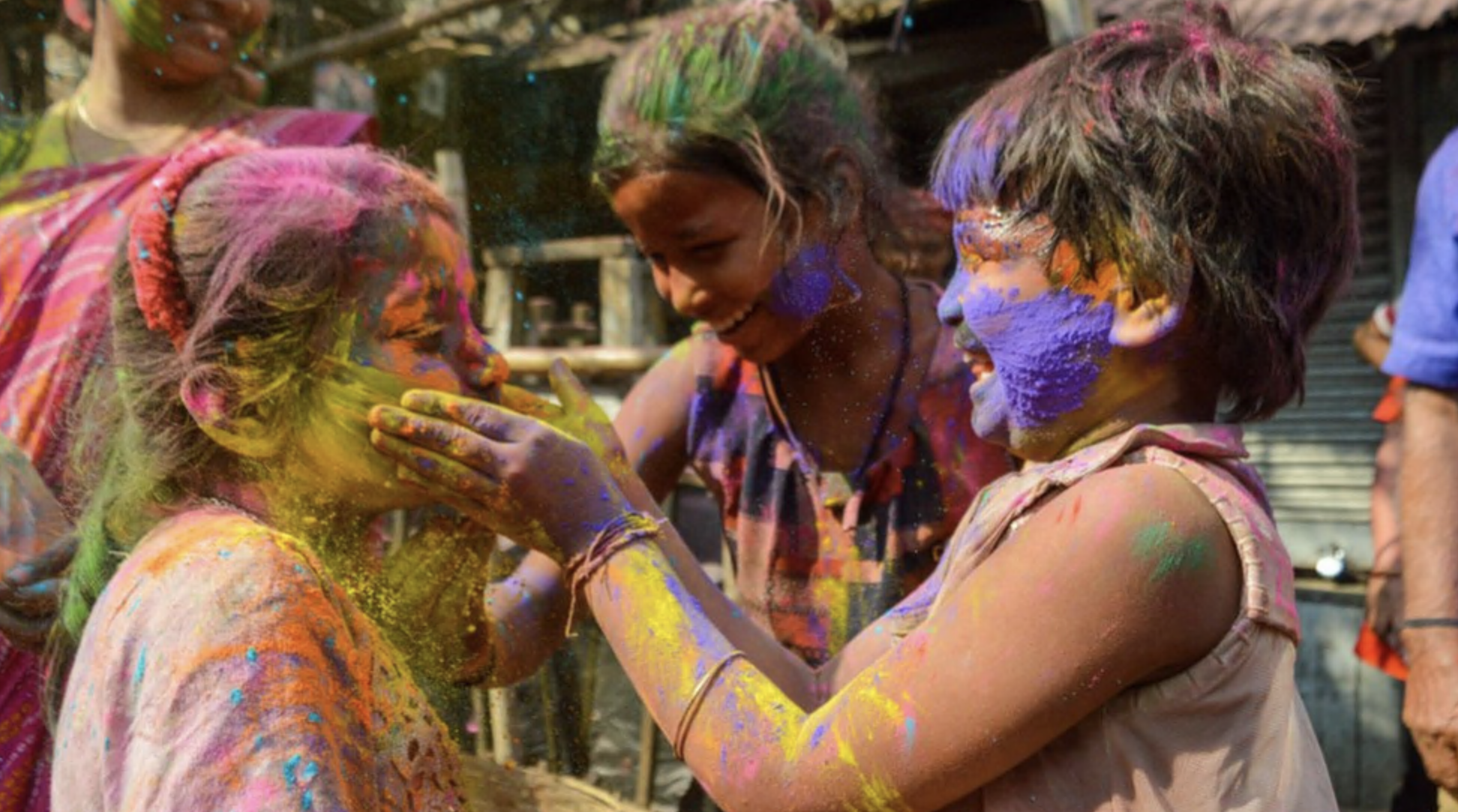Two girls are seen smearing each other with coloured powder