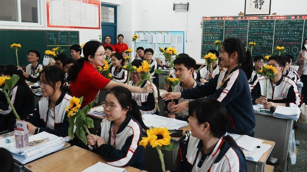 توزع معلمة زهور عباد الشمس على طلابها لتشجيعهم قبل امتحان دخول الكلية الوطنية لعام 2023  في فصل دراسي في مدرسة ثانوية في 1 يونيو/حزيران 2023 في لويانغ بمقاطعة خنان الصينية