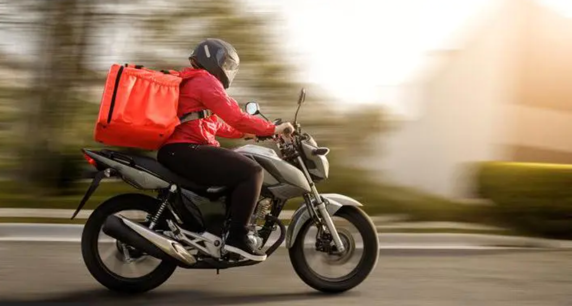 Entregador sobre uma moto portando mochila de entrega de mercadorias