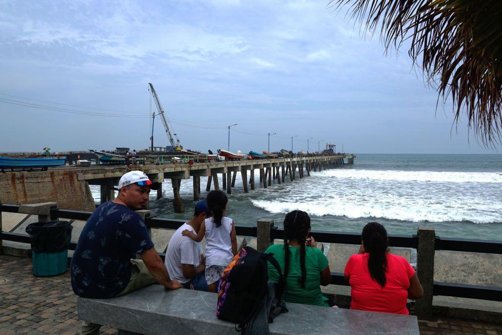 Una familia sentada observa el antiguo muelle que será reemplazado por el nuevo como parte de un complejo turístico financiado por la República Popular China el 7 de junio de 2023 en La Libertad, El Salvador.