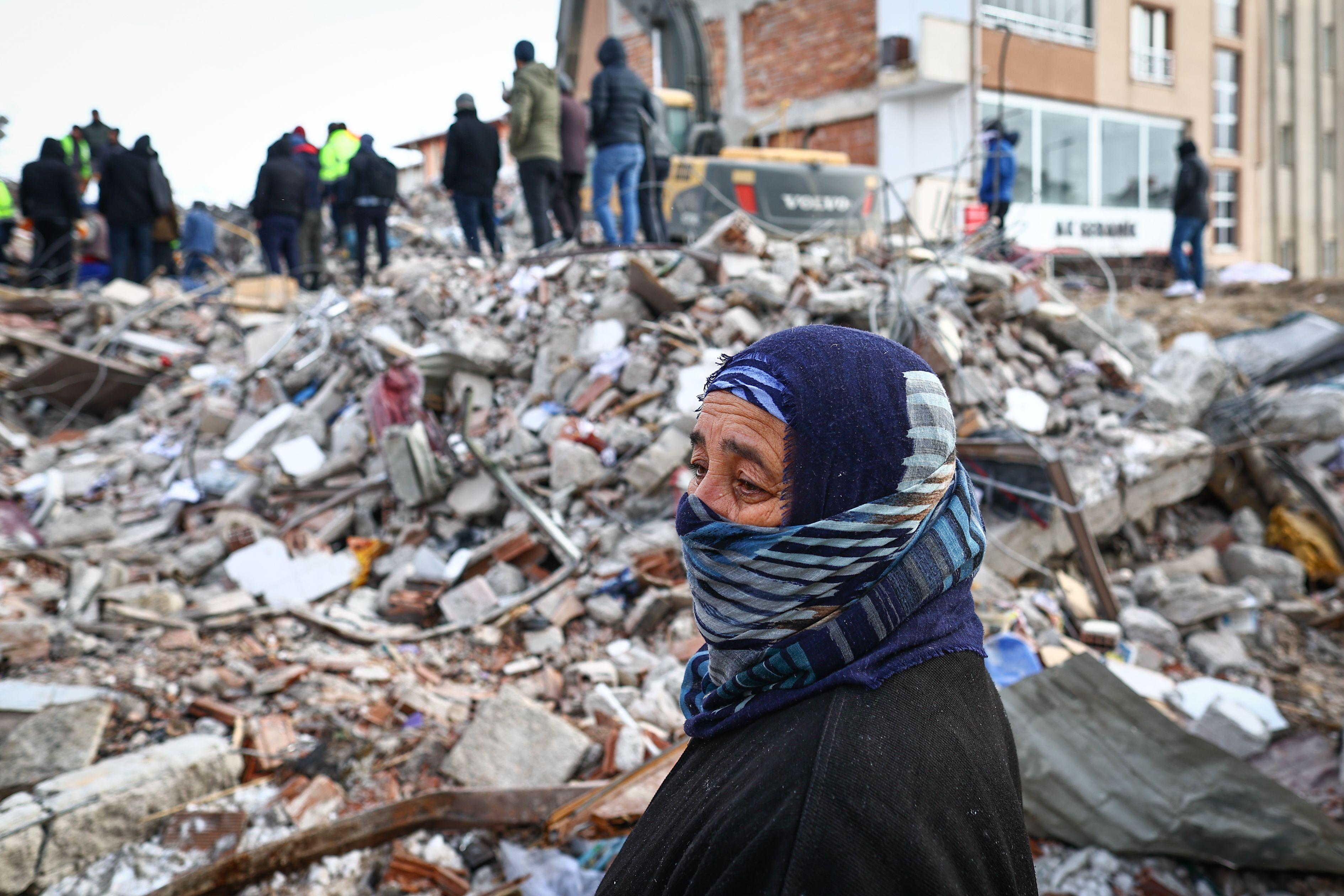 Uma mulher observa enquanto equipes de emergência e moradores locais procuram sobreviventes no local de um prédio que desabou após um grande terremoto no distrito de Elbistan, em Kahramanmaras, Turquia, 08 de fevereiro de 2023.