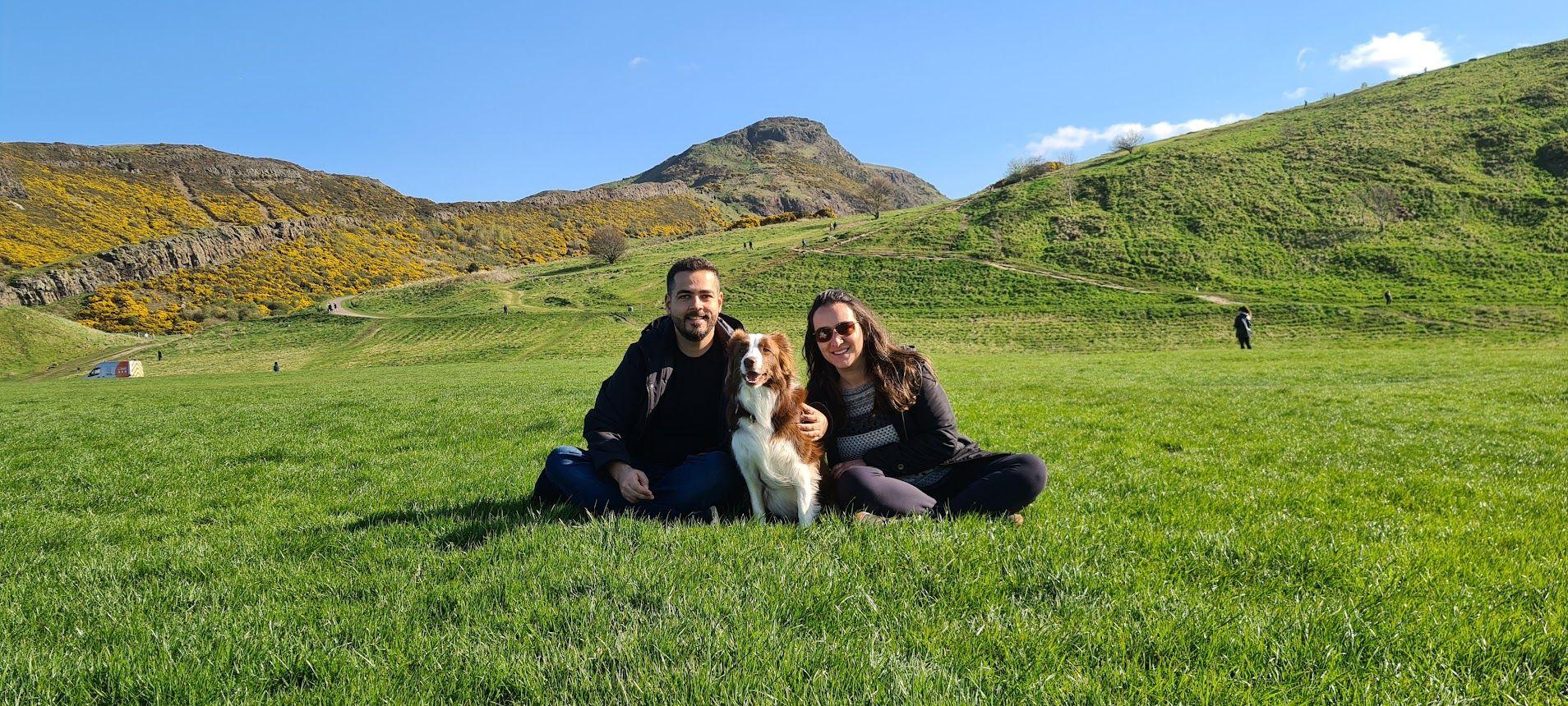 O casal está sentado na grama com a cachorra Gaia 