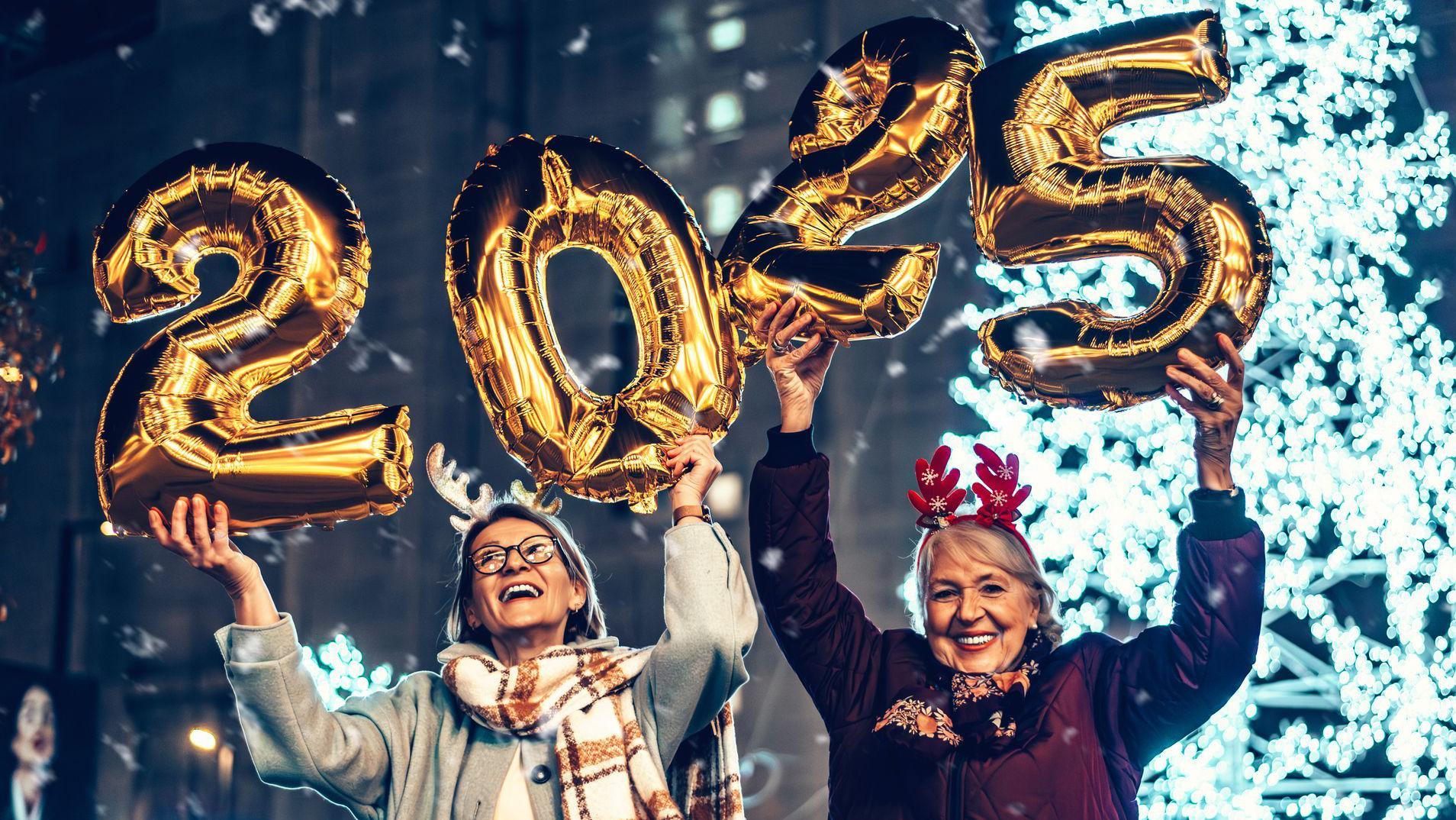 Dos señoras sostienen globos con los números que marcan el año 2025.