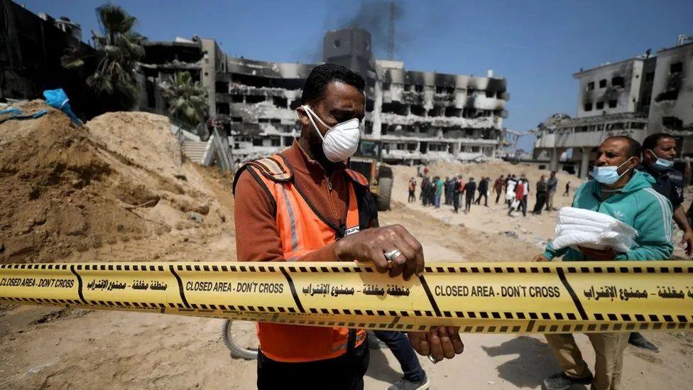 Trabalhadores com máscara em área isolada no pátio do hospital al-Shifa