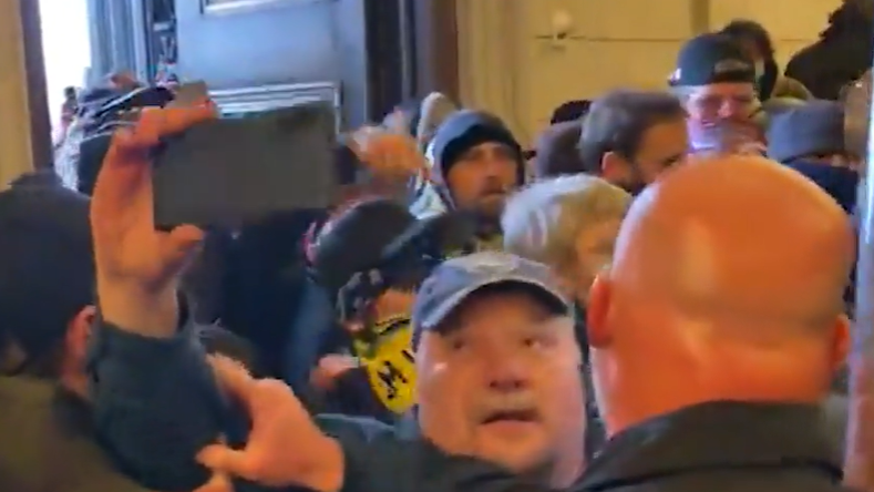 Still de vídeo mostra homem branco de bigode em meio  multidão fazendo gravação com celularJoseph Fischer shown facing police inside the Capitol on 6 January 2021