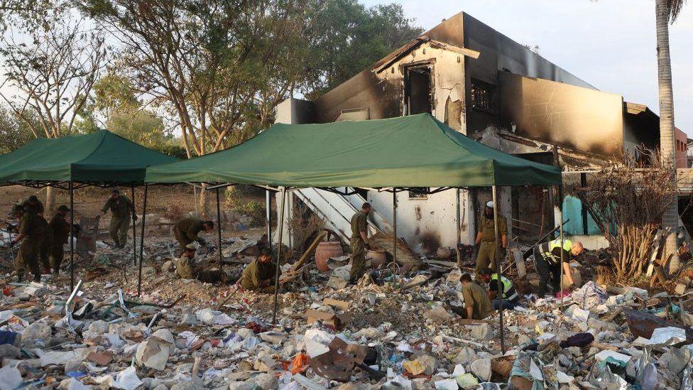 Tentara Israel dan sukarelawan dari tim tanggap darurat Yahudi ultra-Ortodoks Zaka Israel mencari melalui puing-puing di Kibbutz Be'eri dekat perbatasan dengan Gaza pada 12 November 2023, setelah serangan militan Palestina pada 7 Oktober.