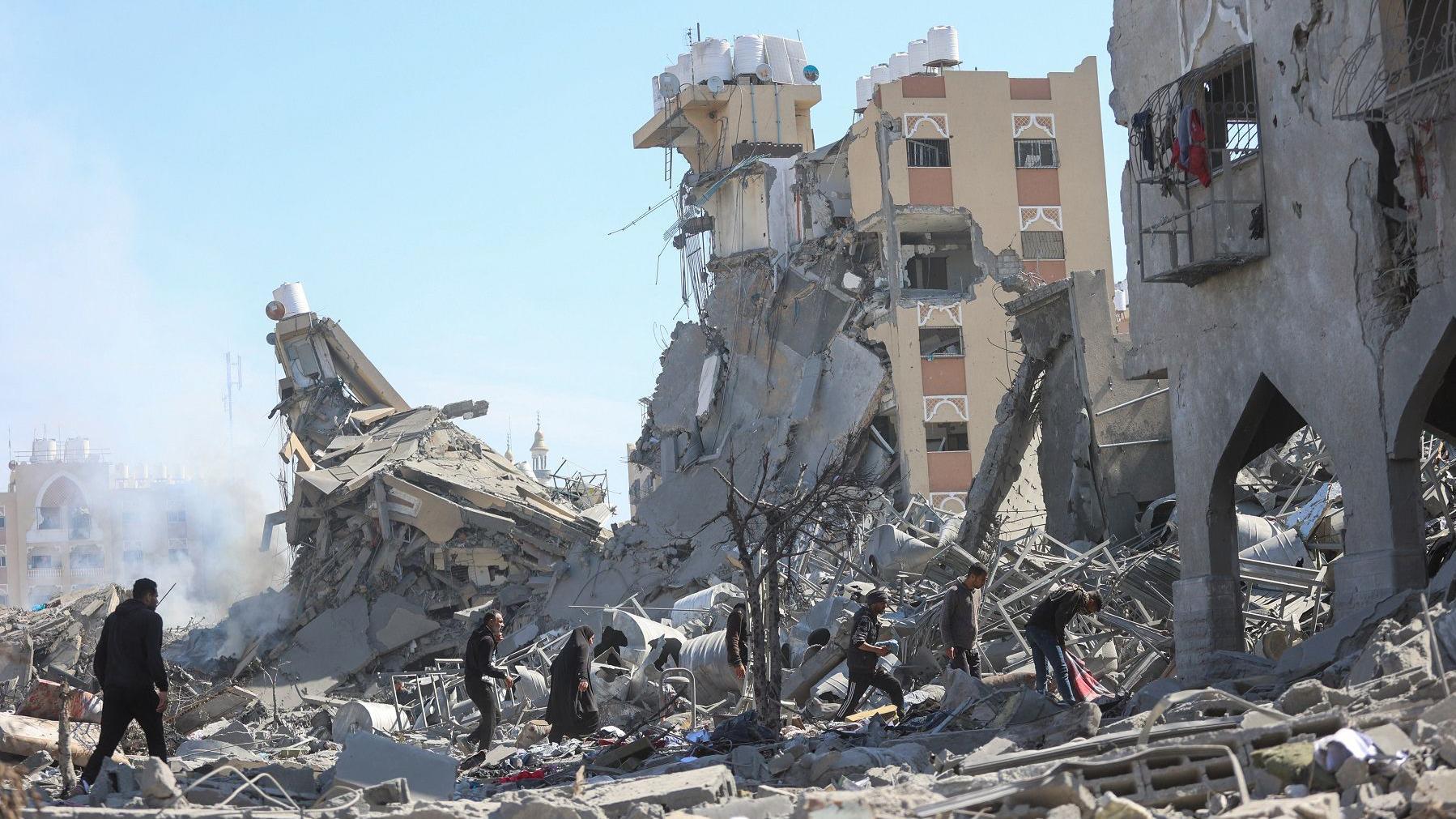 فلسطينيون يتفقدون المباني السكنية المدمرة في أعقاب غارة إسرائيلية