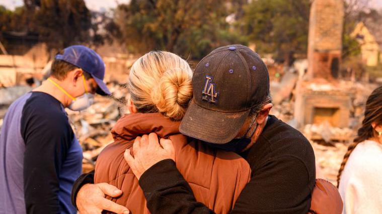 Dos miembros de una familia se abrazan y lloran sobre los escombros quemados de la que era su vivienda, arrasada por el incendio Eaton en Altadena, condado de Los Ángeles, California, Estados Unidos, el 9 de enero de 2025.