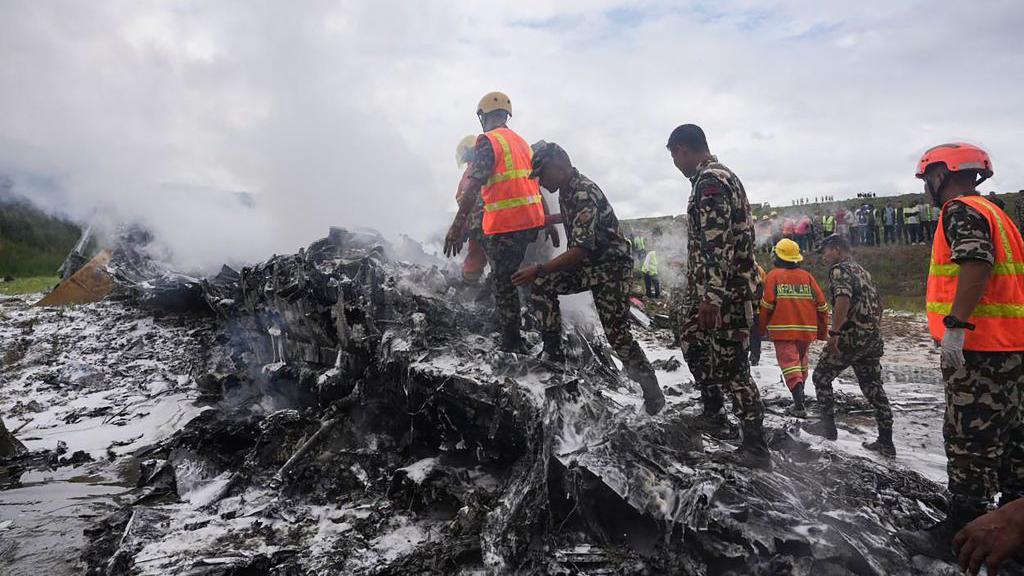 Tim penyelamat dan personel militer berdiri di lokasi reruntuhan pesawat Saurya Airlines yang jatuh saat lepas landas di Bandara Internasional Tribhuvan di Kathmandu pada 24 Juli 2024.