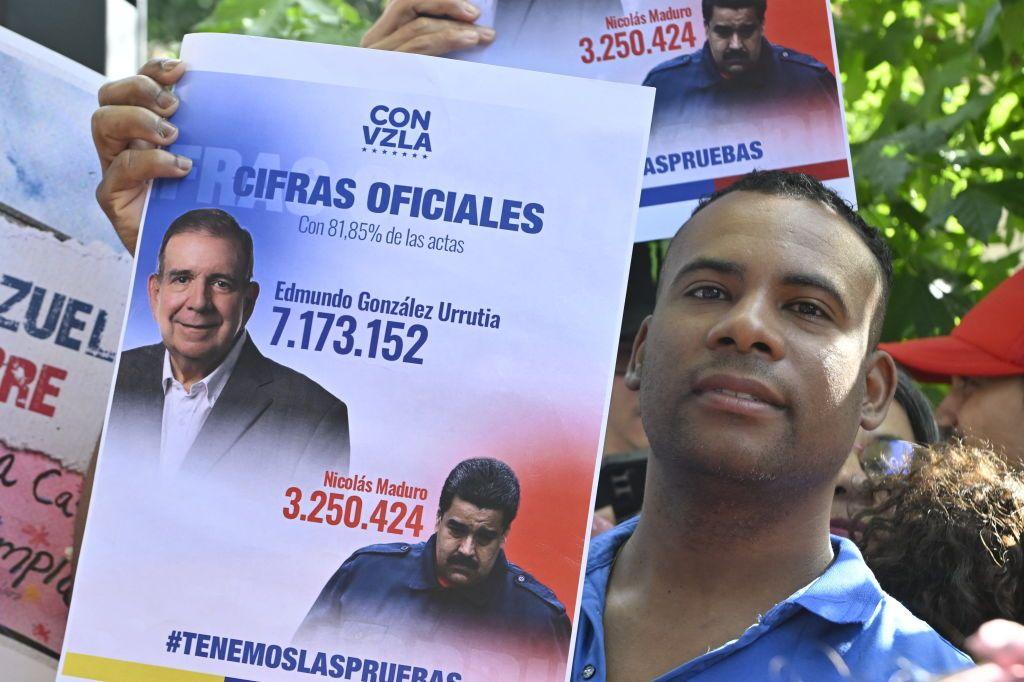 Un hombre con un cartel con supuestos resultados presidenciales de julio