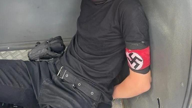 Jovem preso com braçadeira com símbolo nazista