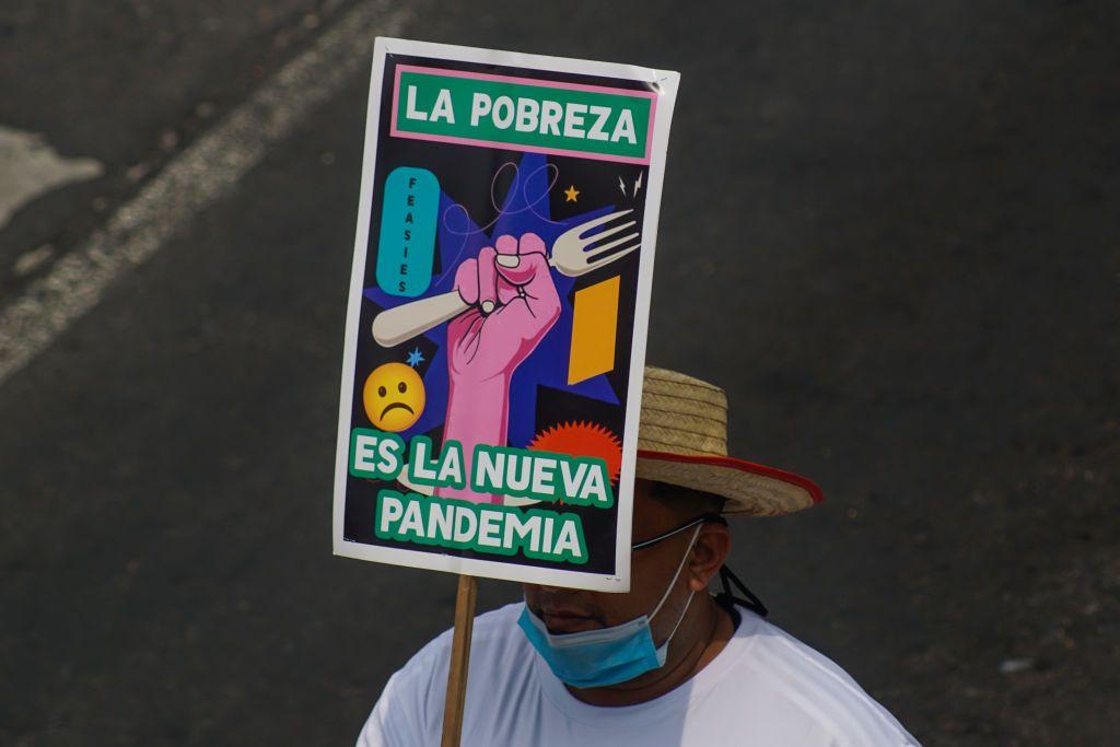 Manifestante con un cartel que dice "la pobreza es la nueva pandemia" durante una protesta el Día del Trabajador, el 1 de mayo de 2023, en San Salvador.