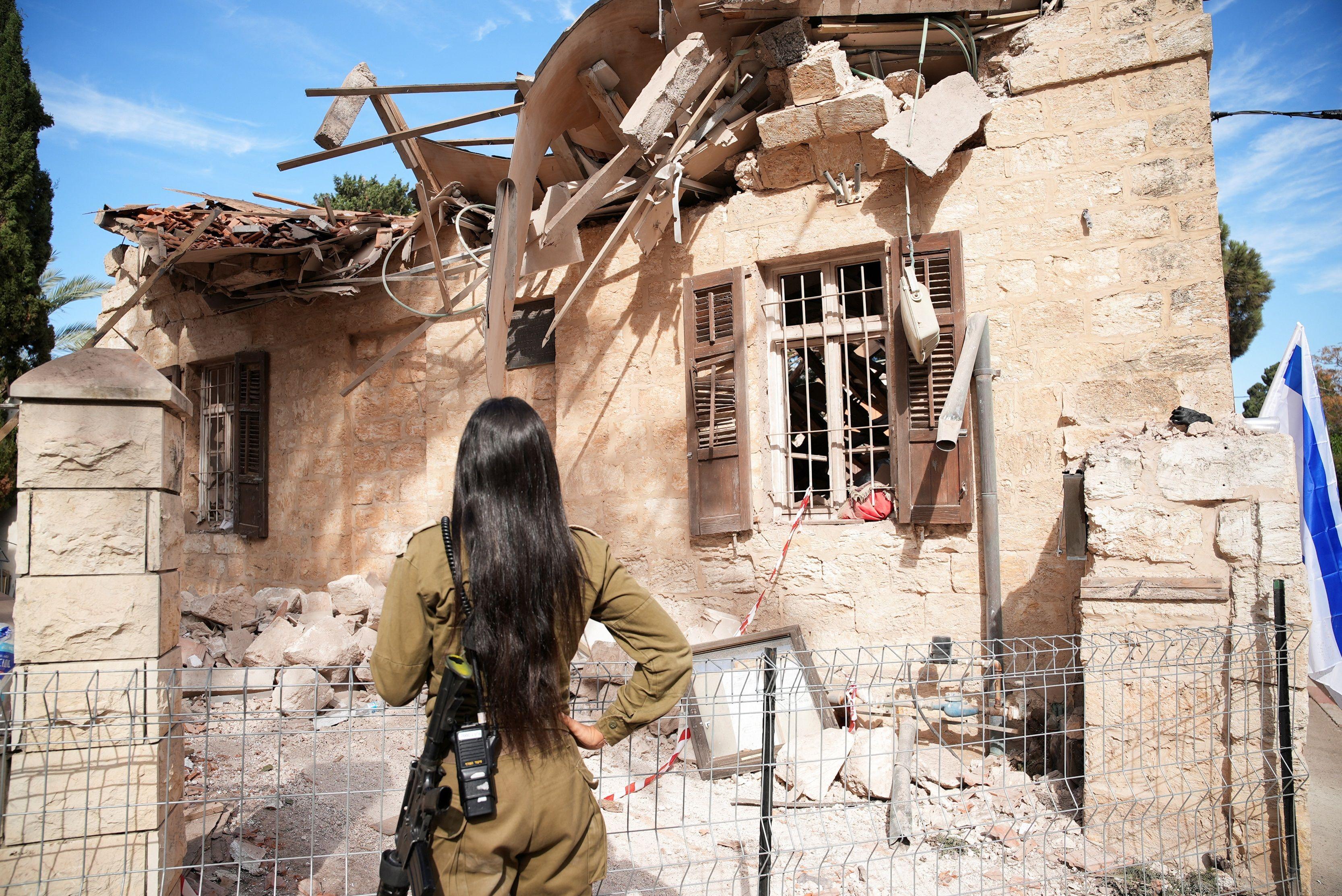 جندية تنظر إلى كنيس يهودي متضرر في اليوم التالي لقصفه عندما سقط مقذوف بعد أن أبلغ الجيش الإسرائيلي عن عبور المقذوفات إلى إسرائيل من لبنان
