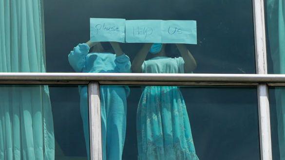 Dos niñas migrantes deportadas desde EE.UU. muestran el mensaje "Por favor ayúdanos" desde un hotel en Ciudad de Panamá.