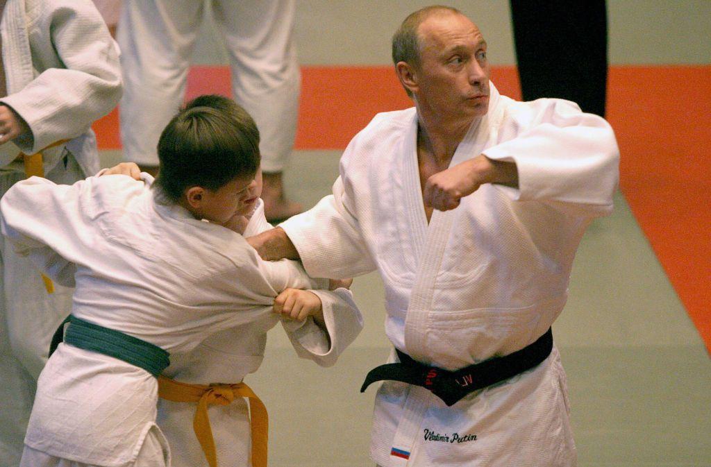 Vladimir Putin,à direita, demonstra um golpe de judô ao lado de dois meninos, durante sua visita a uma escola em São Petersburgo