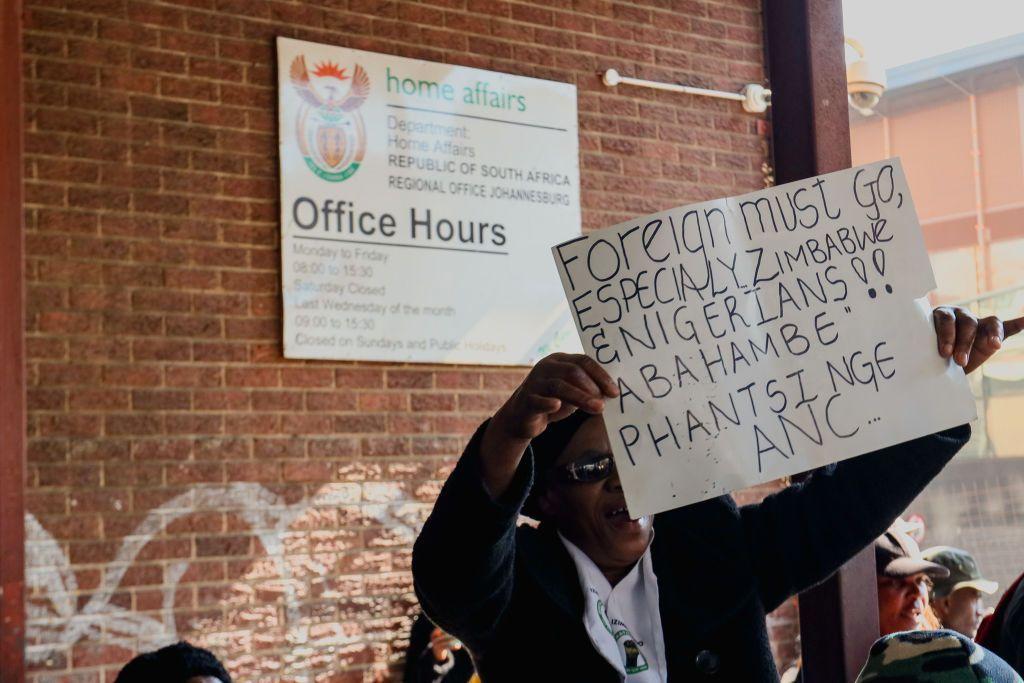 Un hombre con una pancarta en la que se lee: "Los extranjeros deben irse"