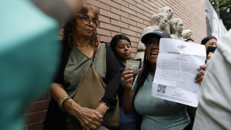 Woman shows her ID with a letter in voting line 