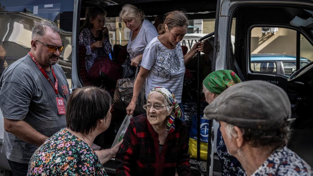 Una anciana recibe ayuda para bajar de un autobús junto con otros evacuados en la ciudad de Sumy.