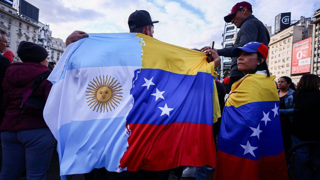 Un venezolano sostiene una bandera mitad de Venezuela y mitad de Argentina durante una marcha en Buenos Aires