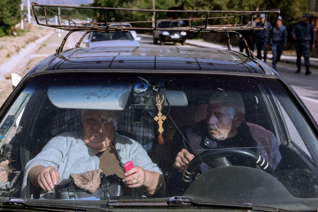 Un hombre y una mujer en un auto cargado con sus pertenencias.