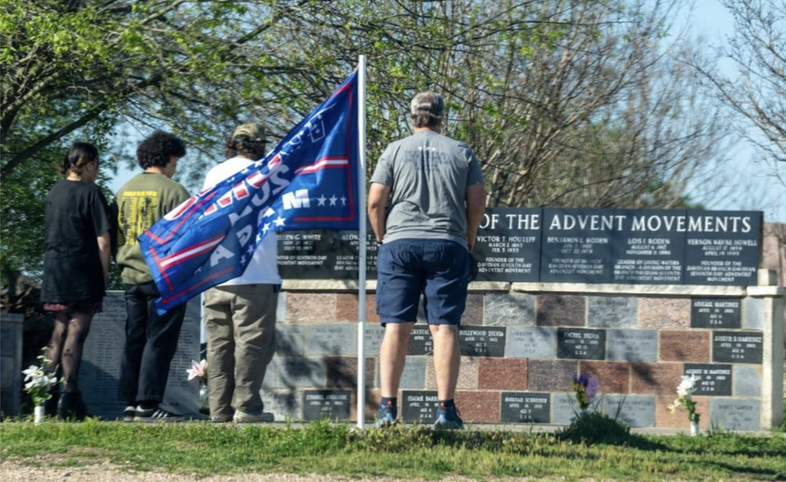 Pessoas de cabeça baixa diante de um monumento aos mortos em Waco