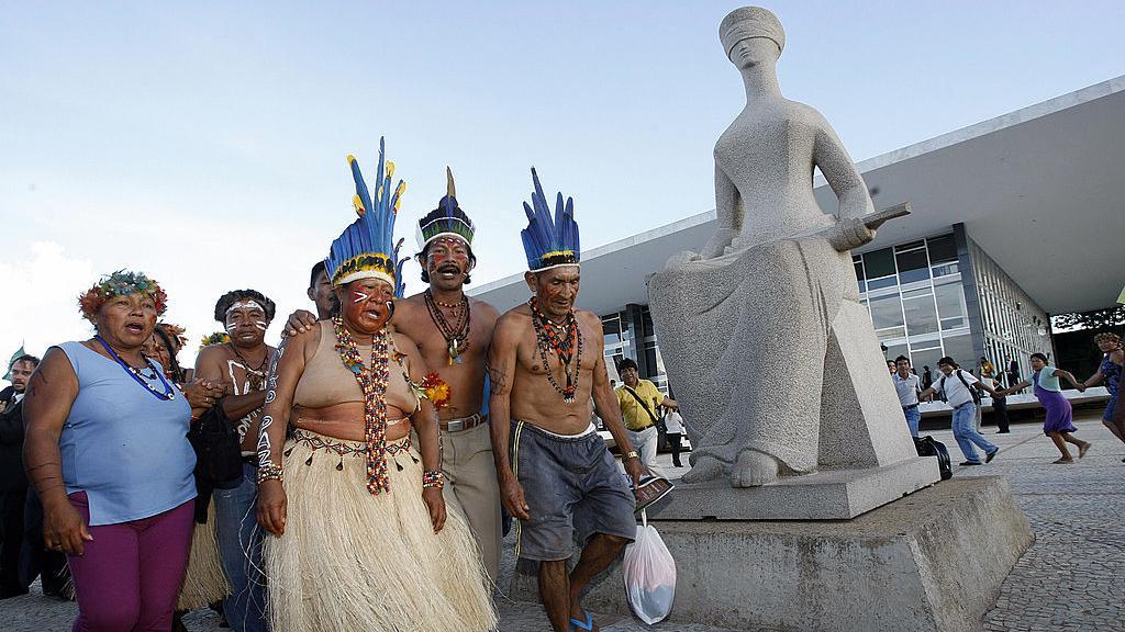 Indígenas ao lado de estátua no STF