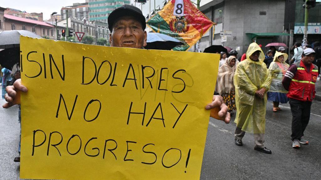 Un manifestante sostiene una pancarta con el texto "Sin dólares no hay progreso".