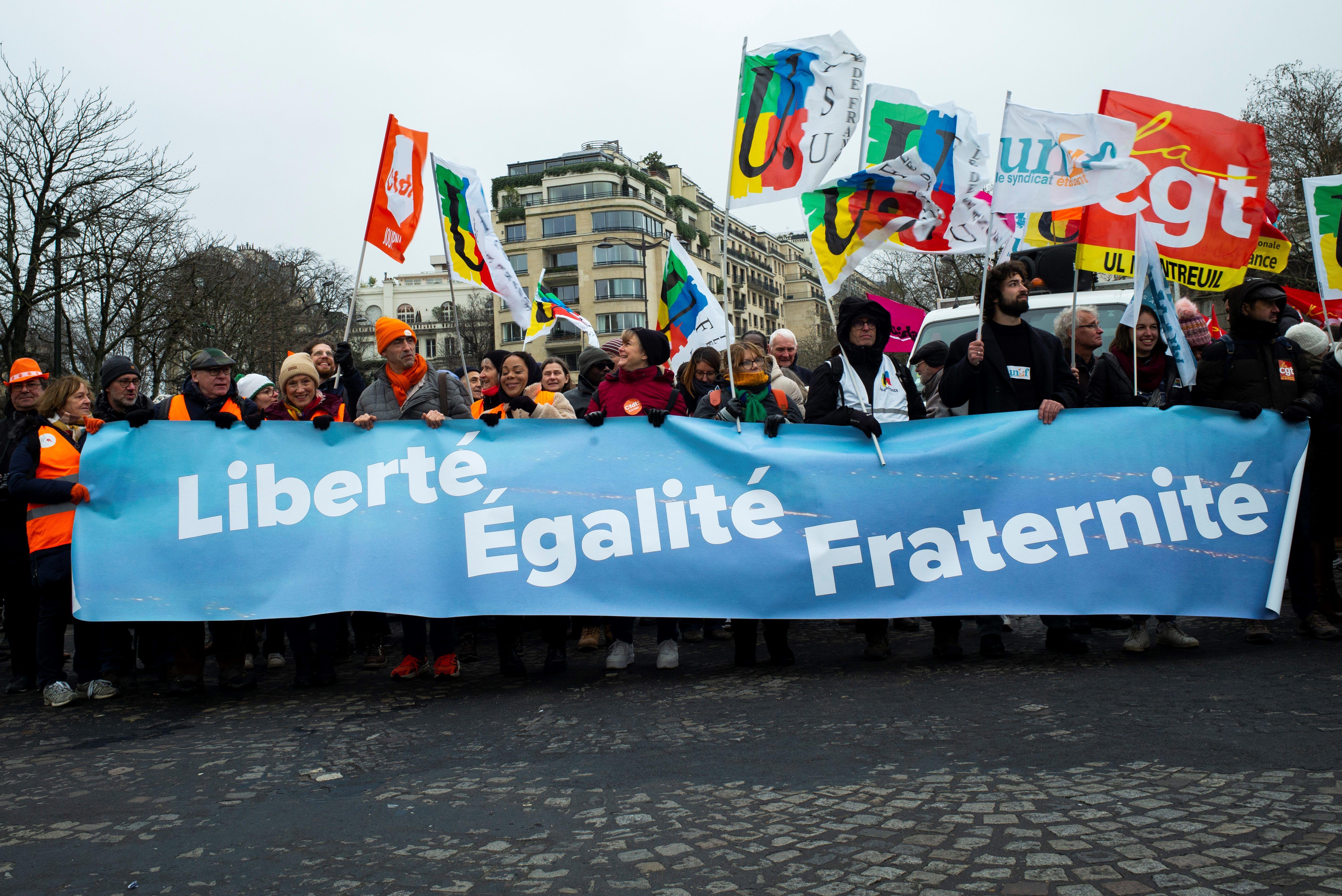 Manifestantes en las calles de francia sostienen una pancarta con el lema "Liberté, Égalité, Fraternité"