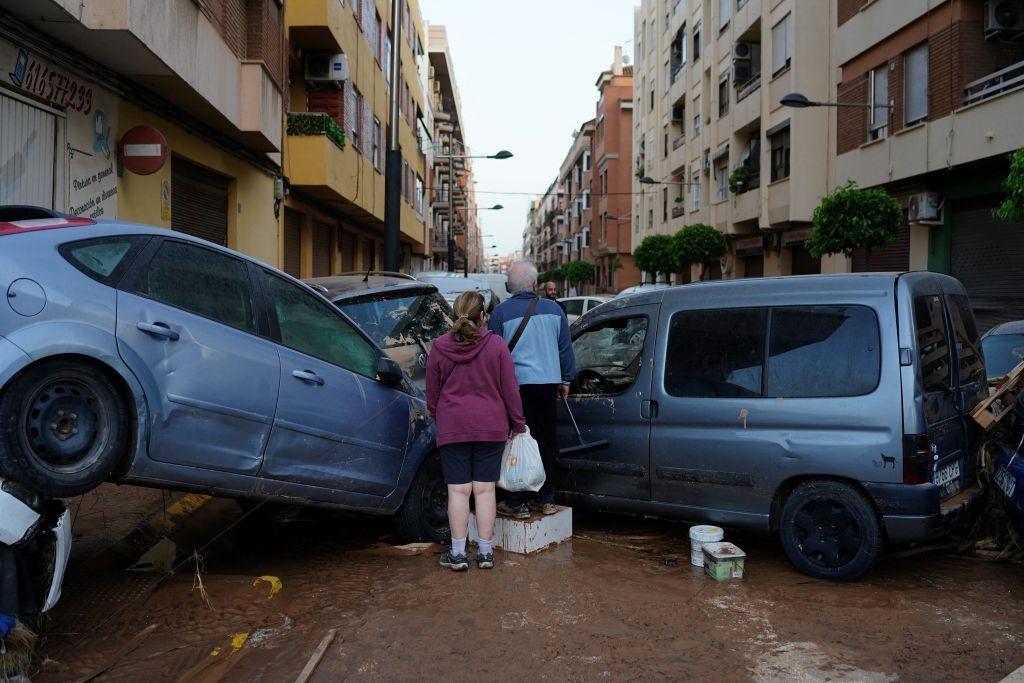 Personas caminando entre autos destruidos.