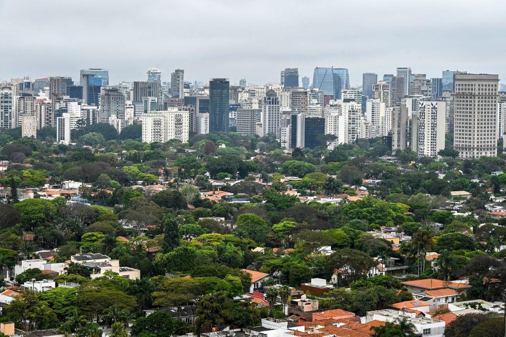 Foto aéres de casas com muitas árvores e prédios ao fundo 