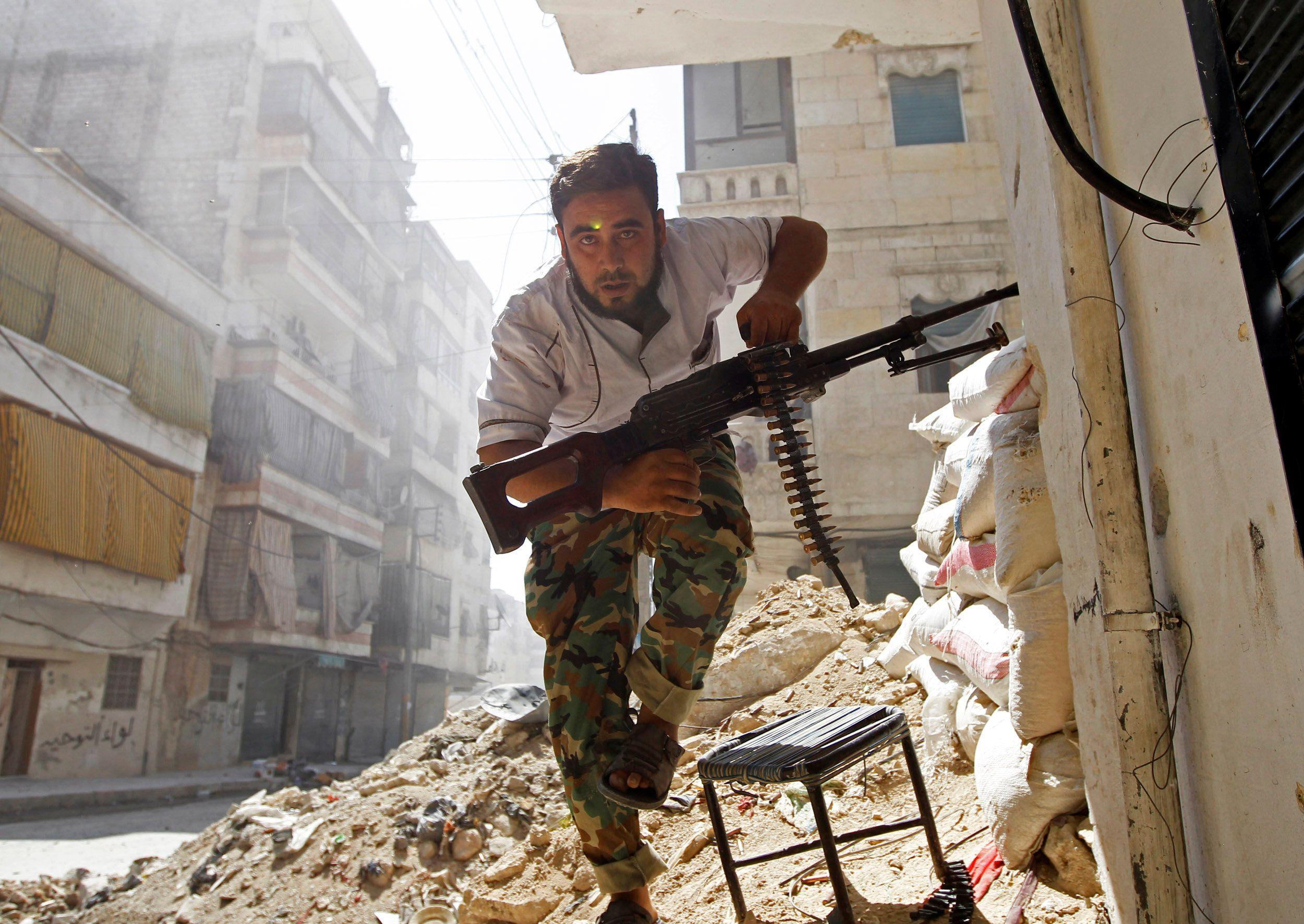 مقاتل من قوات الجيش السوري الحر يحتمي بمبنى خلال اشتباكات مع الجيش السوري في حي صلاح الدين بوسط حلب في أغسطس/آب 2012