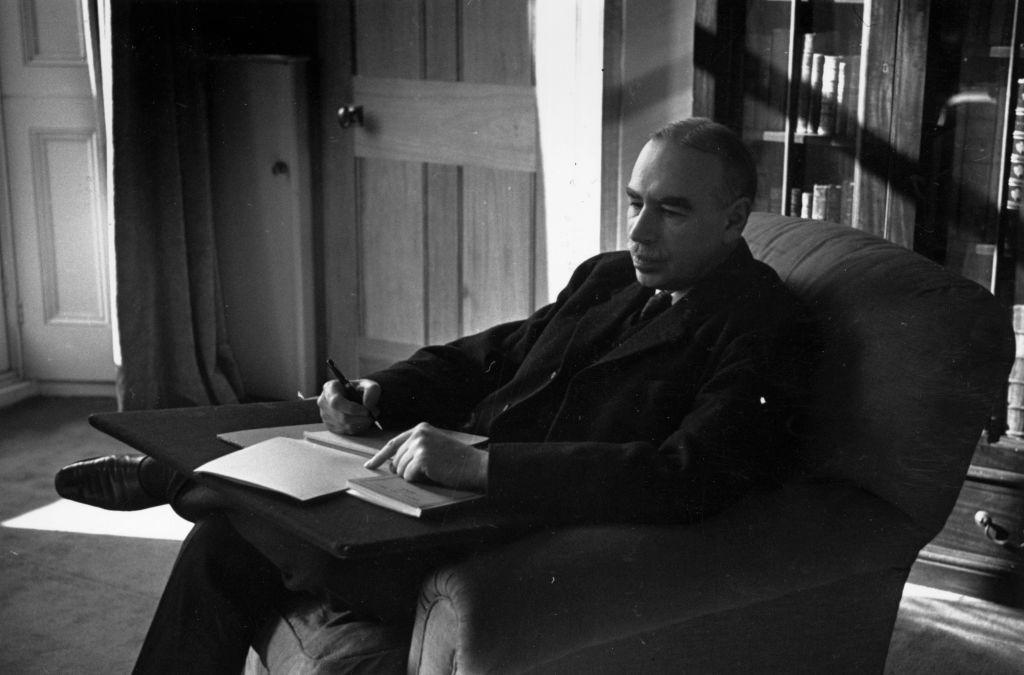 Keynes toma notas sentado en un sofá