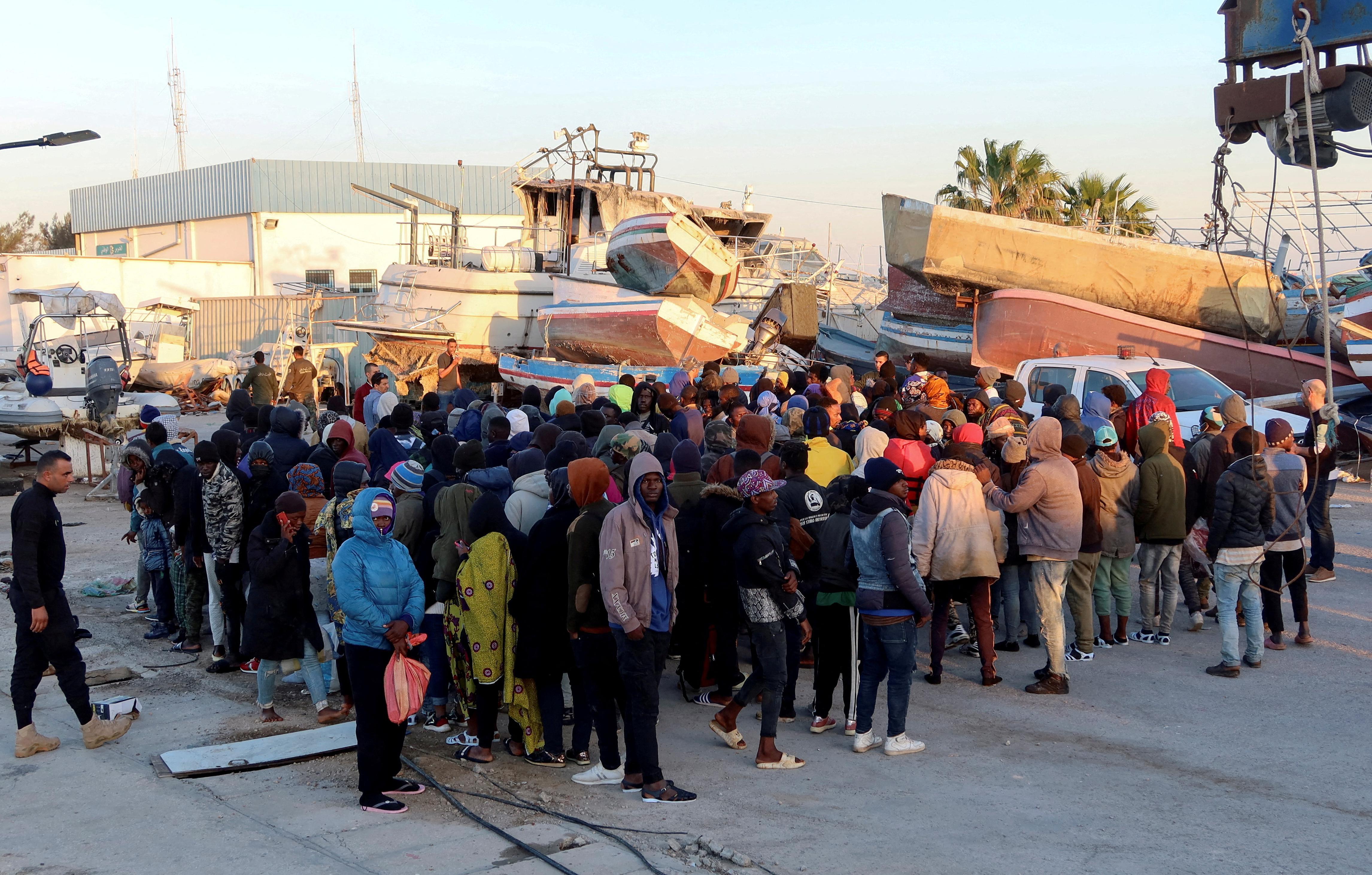  مهاجرون ينتظرون في ميناء صفاقس بعد أن أوقفهم خفر السواحل التونسي في البحر أثناء محاولتهم العبور إلى إيطاليا.