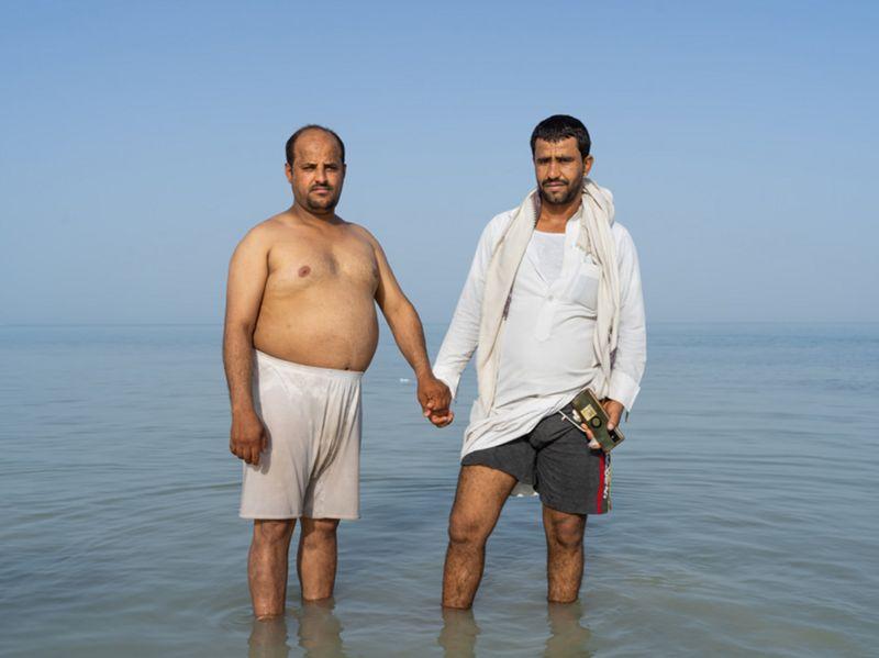 Dois homens de mãos dadas em pé no mar