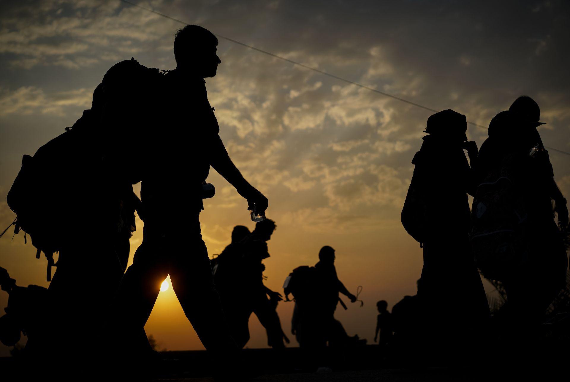 Grupo de pessoas com mochila nas costas caminhando ao entardecer