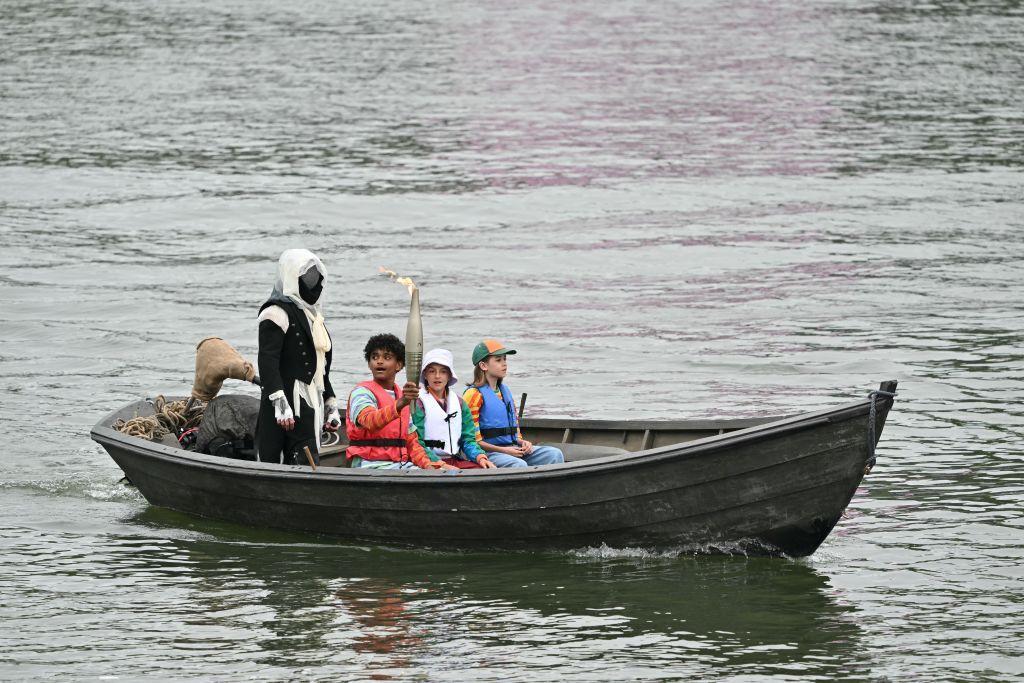 Niños llevan la antorcha olímpica en un barco sobre el río Sena durante la inauguración de los Juegos Olímpicos París 2024.