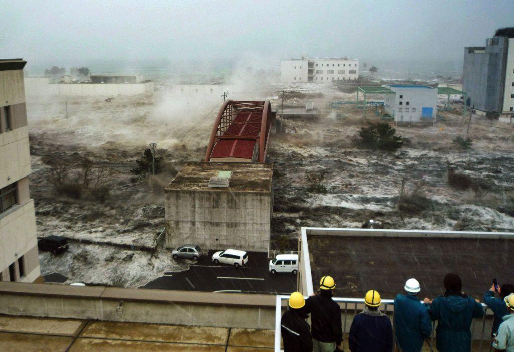 Tsunami menerjang kendaraan dan rumah di sebuah jembatan di kota Sendai di prefektur Miyagi.