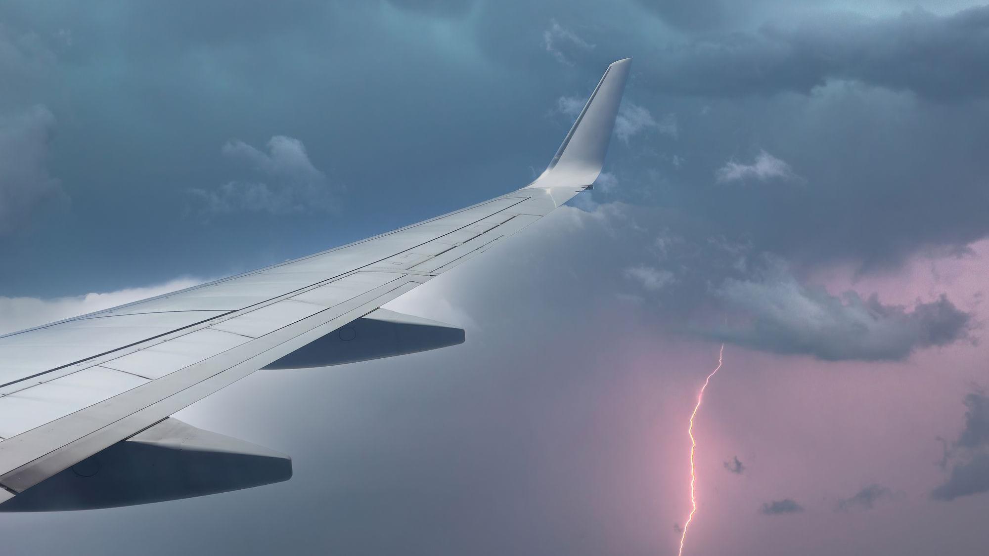 Asa de avião em meio a chuva com raios