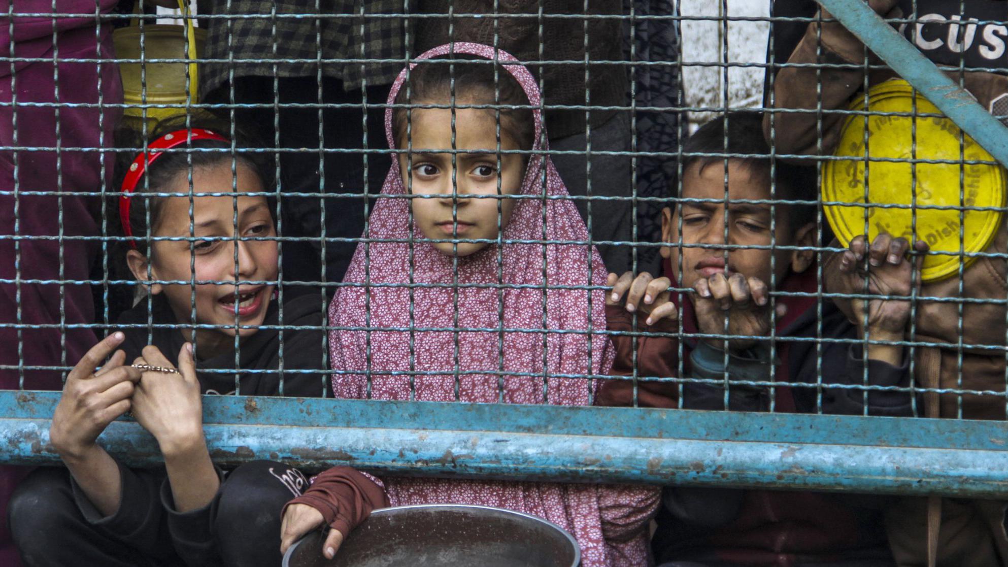 Niños palestinos con ollas vacías esperan comida en Gaza