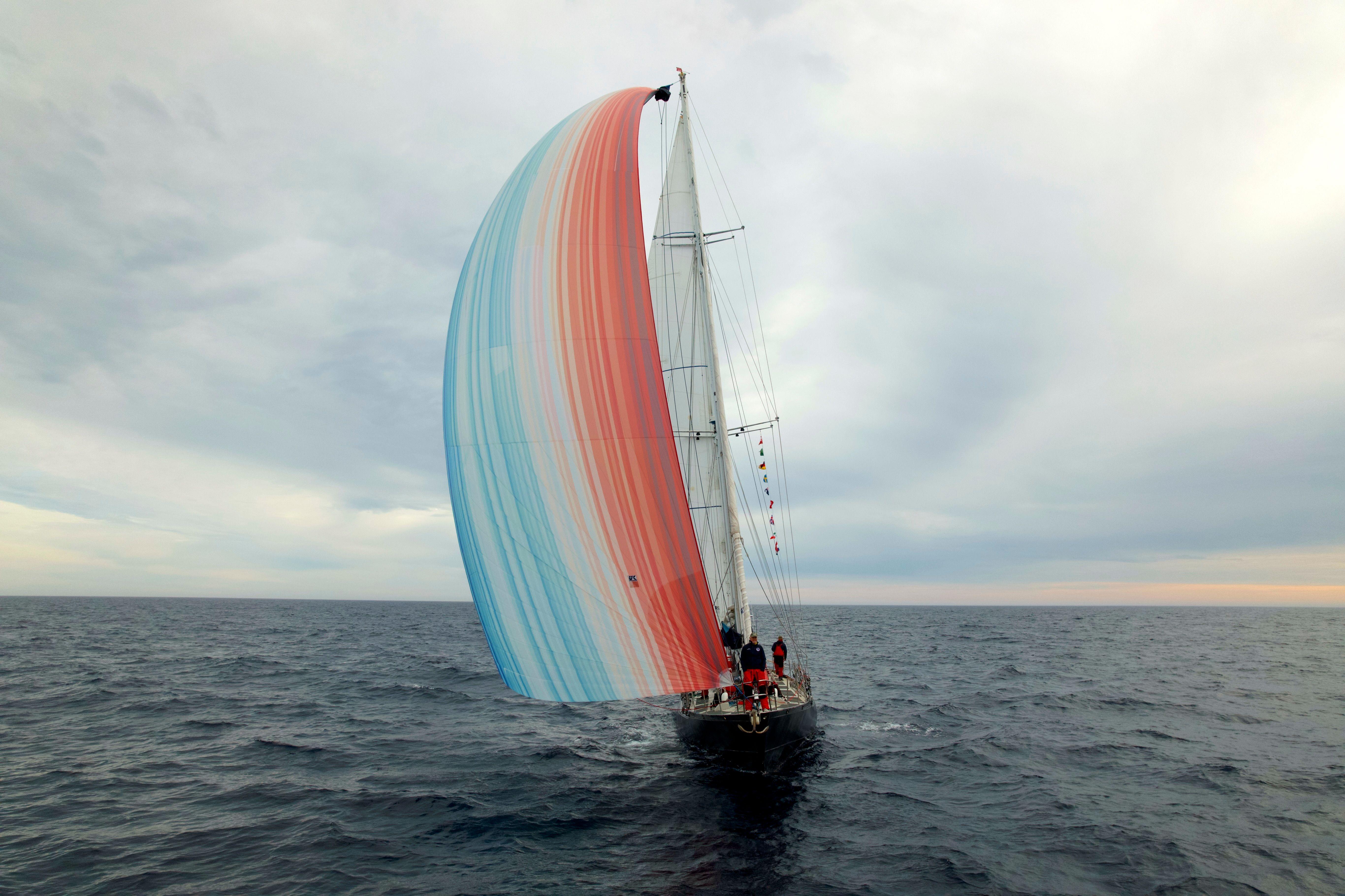 Imagen de un yate navegando en el océano con las rayas climáticas impresas en la vela
