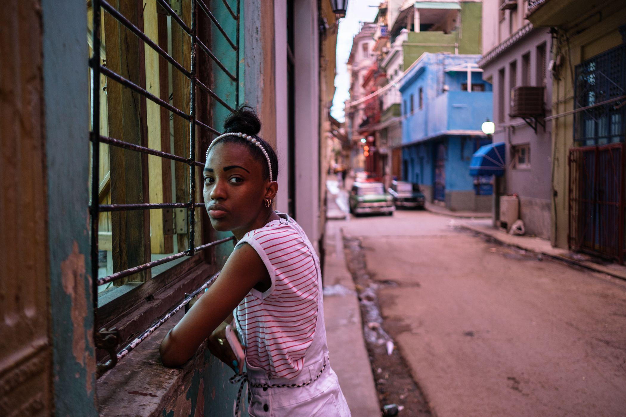 Retrato de una joven afuera de un salón de uñas en las calles de la Habana Vieja.