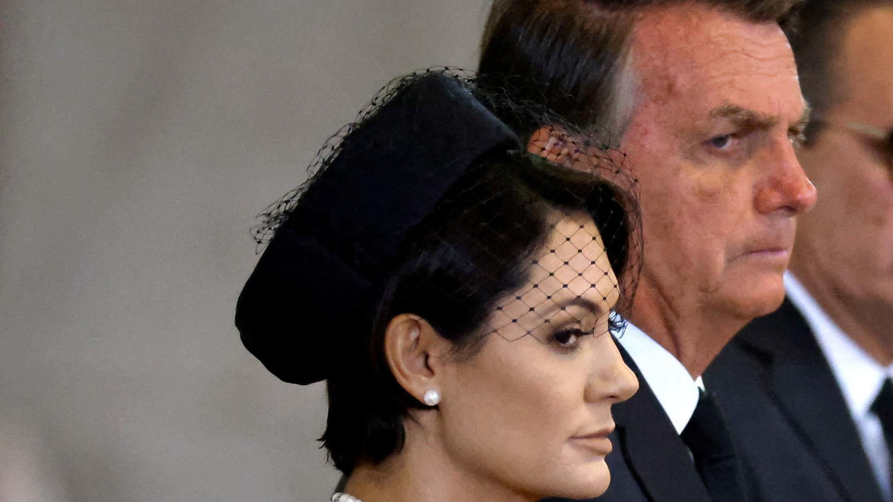 Michelle e Jair Bolsonaro com olhar fechado e trajes formais e fúnebres