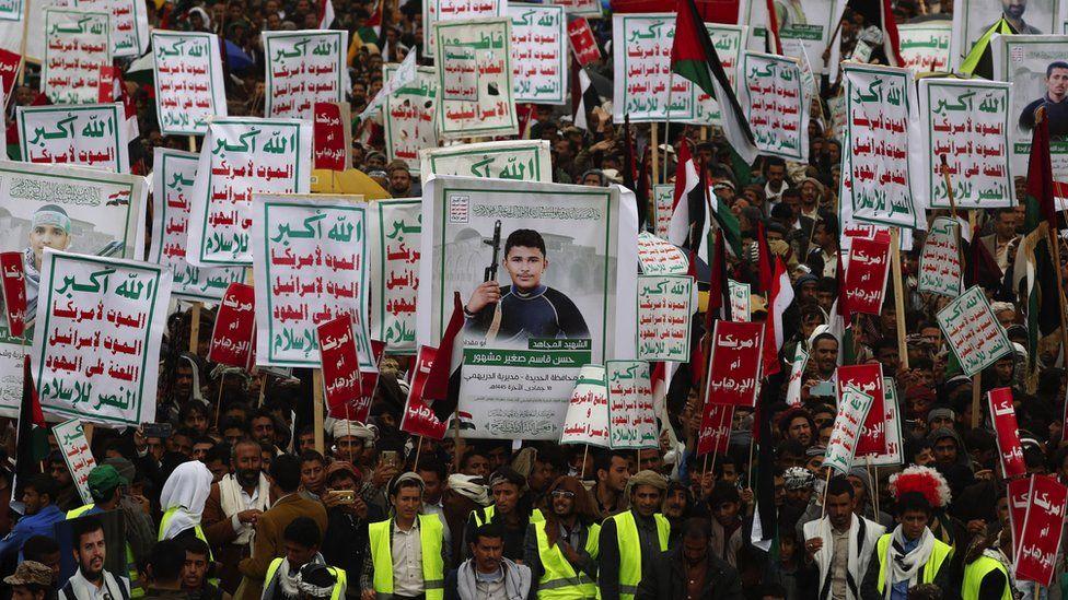 Para pengunjuk rasa membawa spanduk dengan foto pejuang Houthi yang tewas dan meramaikan jalanan.