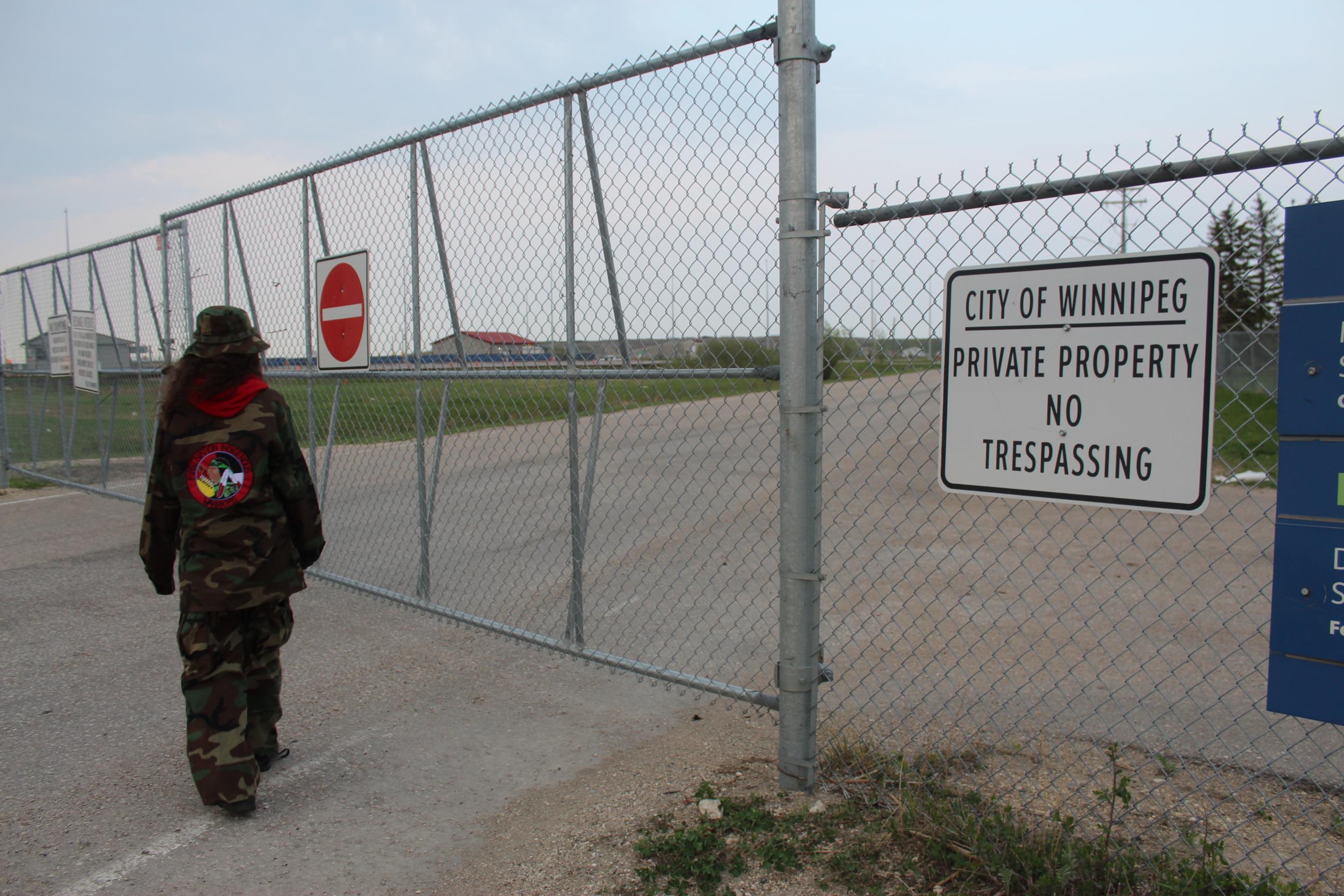 Cambria Harris behind the fence that surrounds the landfill site where her mother is buried in Winnipeg, Canada.