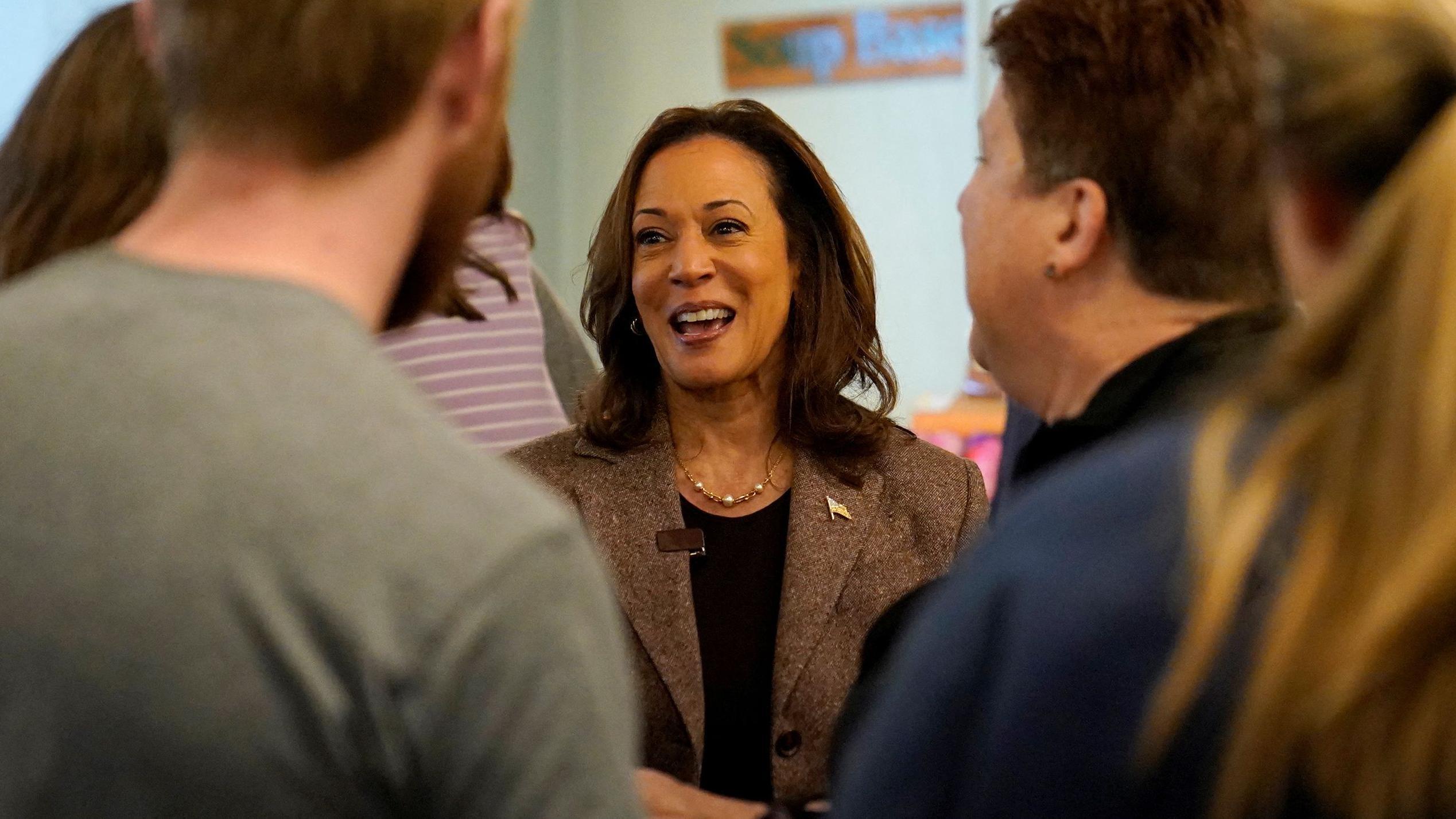 Kamala Harris sorri enquanto conversa com outras pessoas