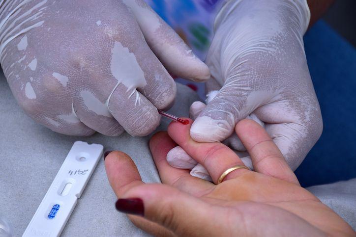 Enfermeira coleta sangue no dedo de paciente para teste rápido