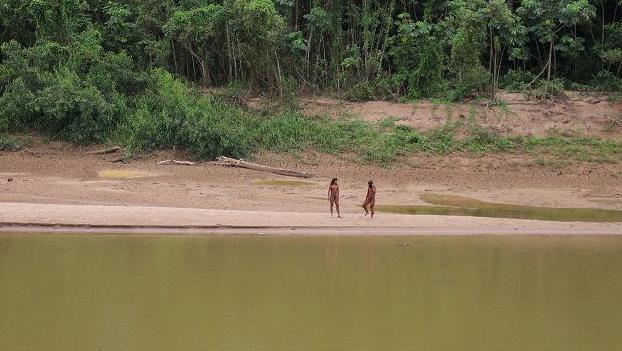Jovenes indígenas al lado de un río. 